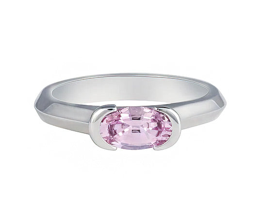 Platinum ring with slight knife edge through band, with oval pink sapphire. The sapphire lies across the finger and is bezel set at both ends. 