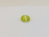 Small round green-yellow Cat's Eye Chrysoberyl gem with white stripe across centre, white background.