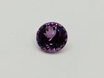 Medium round deep purple spinel gem, on white background.