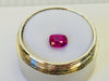 Small rectangle fuschia pink sapphire gem, white background in gem jar.