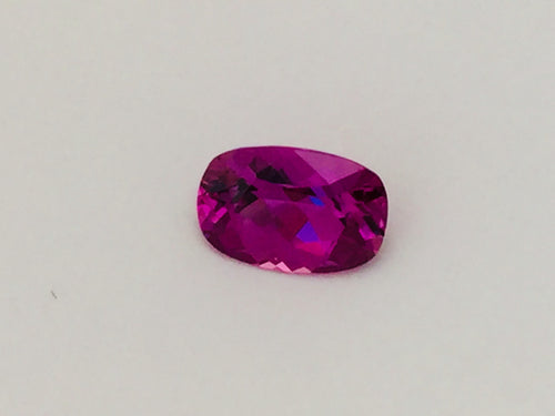 Small rectangle vivid pink sapphire gem, white background.