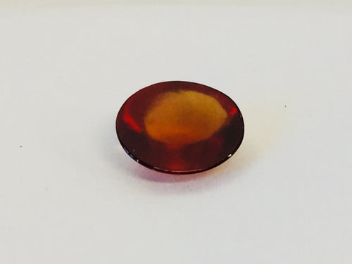 Medium oval deep orange red hessonite garnet gem, white background.