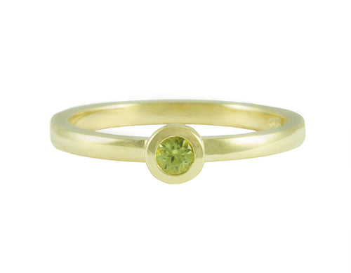 Thin 18 karat green gold band with soft matte finish set with bright green round peridot. Gem set in a frame that sits on the band.