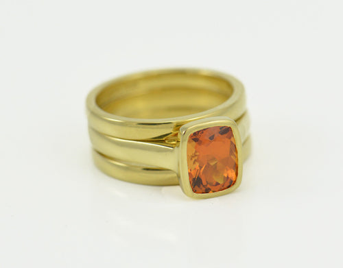 Rectangle orange gem set in green gold with matching green gold bands.