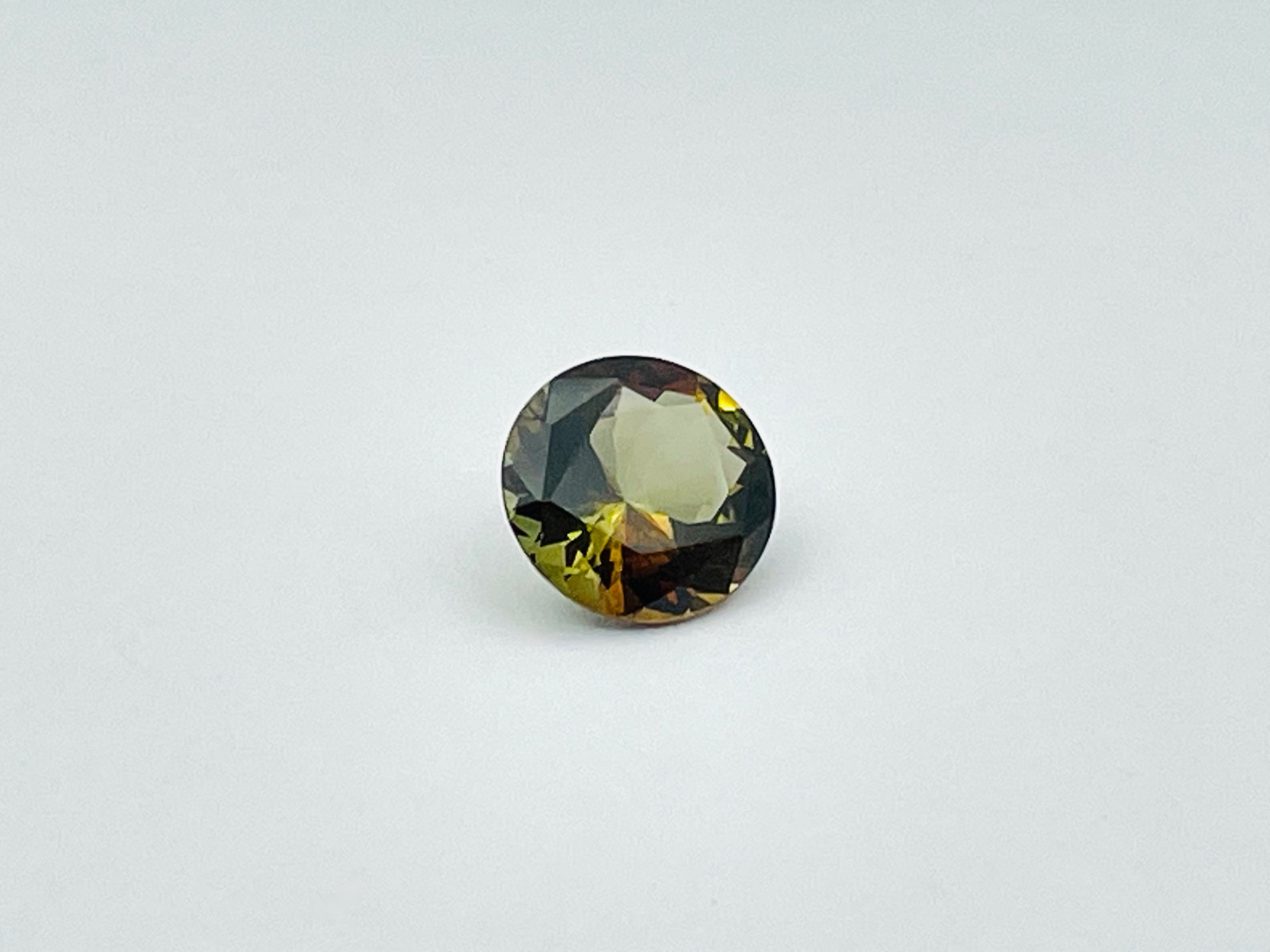 Caramel, brown, green Andalusite gem, round.