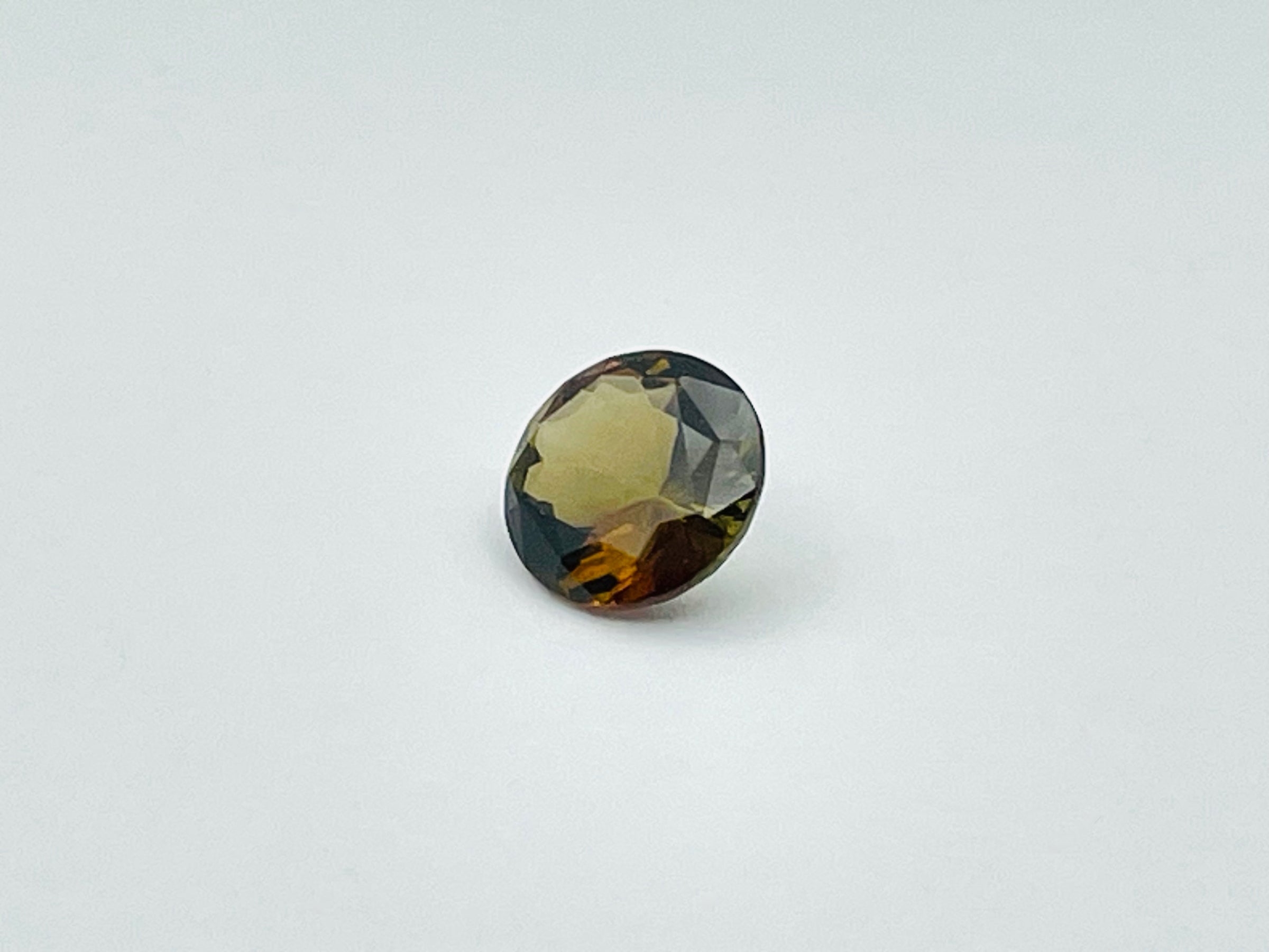 Caramel, brown, green Andalusite gem, round.