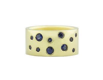 Very wide green gold band with a scattering of various sized sapphires across the face.