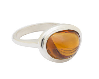 Large silver ring with oval orange gem.