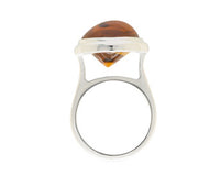 Large silver ring with oval orange gem.