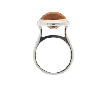 Large silver ring with oval orange gem.