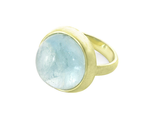 Very large green gold ring set with large round cabochon of blue aquamarine. Gem is set in frame and goes just beyond width of finger.