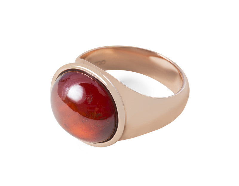 Rose gold ring set with medium oval cabochon of deep orange spessartite garnet. Gem is set in frame and lies across the finger.