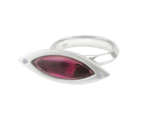 Long cabochon of rich pink tourmaline coming to point at both ends, set in frame of 18 karat white gold with two accent diamonds in frame.