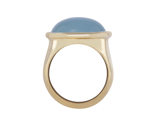Green gold ring with oval cabochon of aquamarine.  The gem is set across the finger and surrounded by rolled rim bezel.