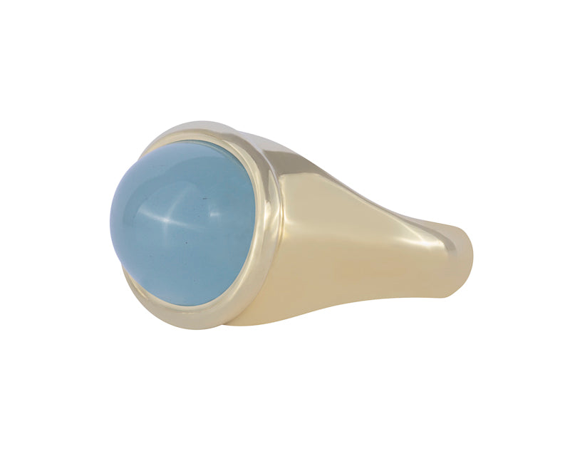 Green gold ring with oval cabochon of aquamarine.  The gem is set across the finger and surrounded by rolled rim bezel.
