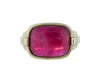 Large green gold ring with overlapping ribbon of gold around the band set with large rectangle cabochon of deep pink tourmaline. Gem lies across the finger.