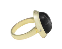 Very large round cabochon of deep grey star sapphire.  Gem is set in a skirt-like bezel with four accent diamonds.