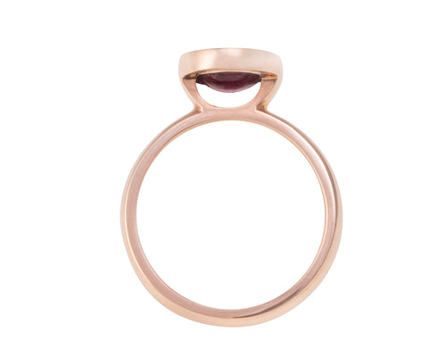 Small oval raspberry red rhodolite garnet upside down in rose gold ring..