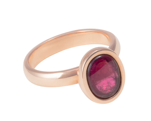Small oval raspberry red rhodolite garnet upside down in rose gold ring..