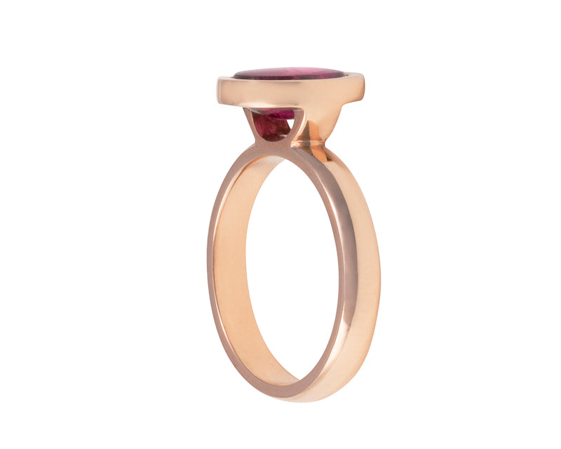 Small oval raspberry red rhodolite garnet upside down in rose gold ring..