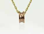Rose gold bead shaped like spool of thread, on yellow gold chain