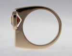 Small rectangle orange gem off-set in rose gold ring.