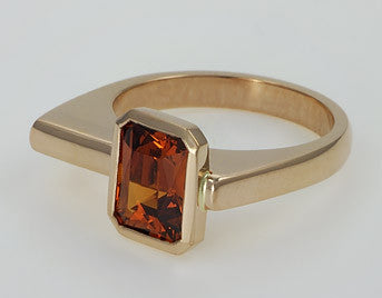 Deep orange rectangular spessartite garnet off set in rose gold ring.