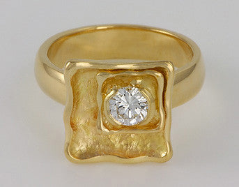 Round diamond set in two squares on yellow gold ring.