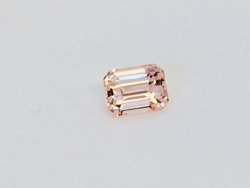 Small rectangular peach-pink sapphire gem, on white background.