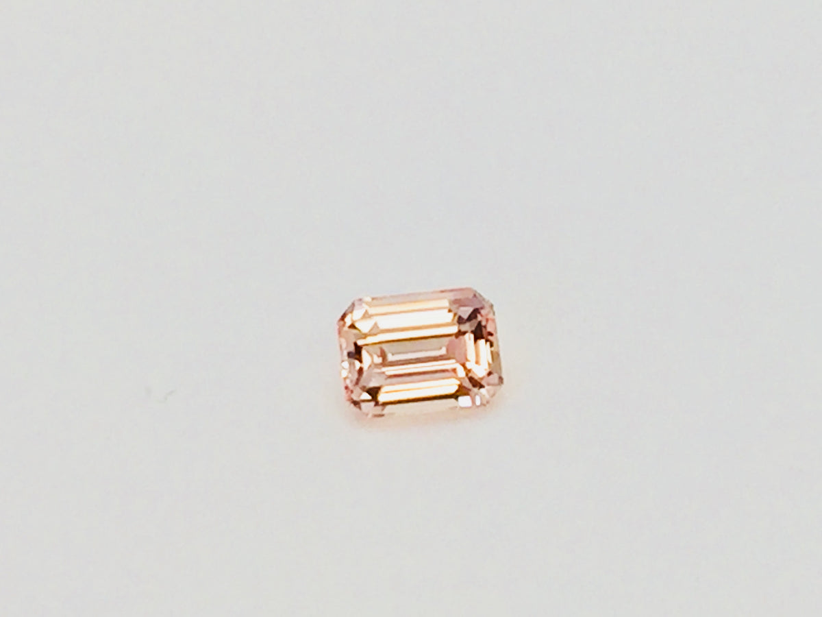 Small rectangular peach-pink sapphire gem, on white background.