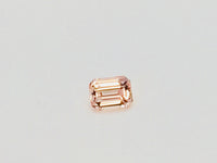 Small rectangular peach-pink sapphire gem, on white background.