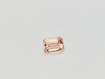 Small rectangular peach-pink sapphire gem, on white background.