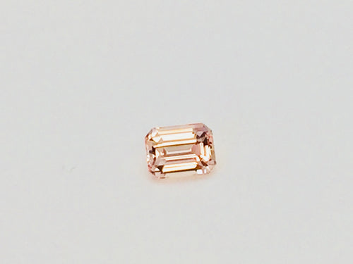 Small rectangular peach-pink sapphire gem, on white background.