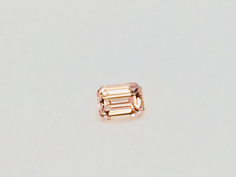 Small rectangular peach-pink sapphire gem, on white background.