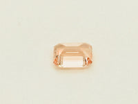 Small rectangular peach-pink sapphire gem, on white background.