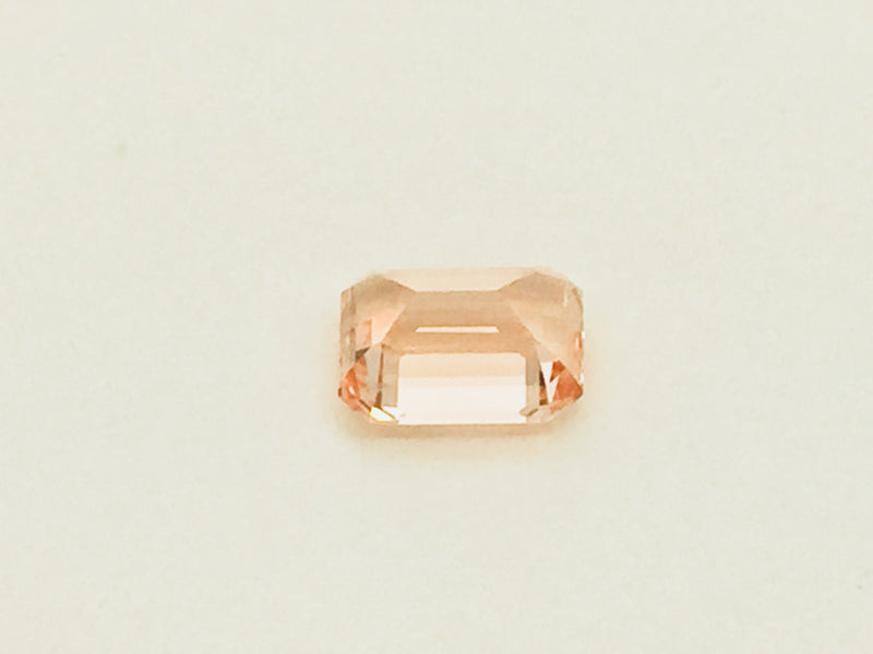 Small rectangular peach-pink sapphire gem, on white background.