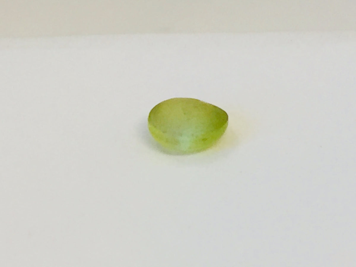Small round green-yellow Cat's Eye Chrysoberyl gem with white stripe across centre, white background.