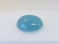Large oval light blue cabochon aquamarine gem, white background.