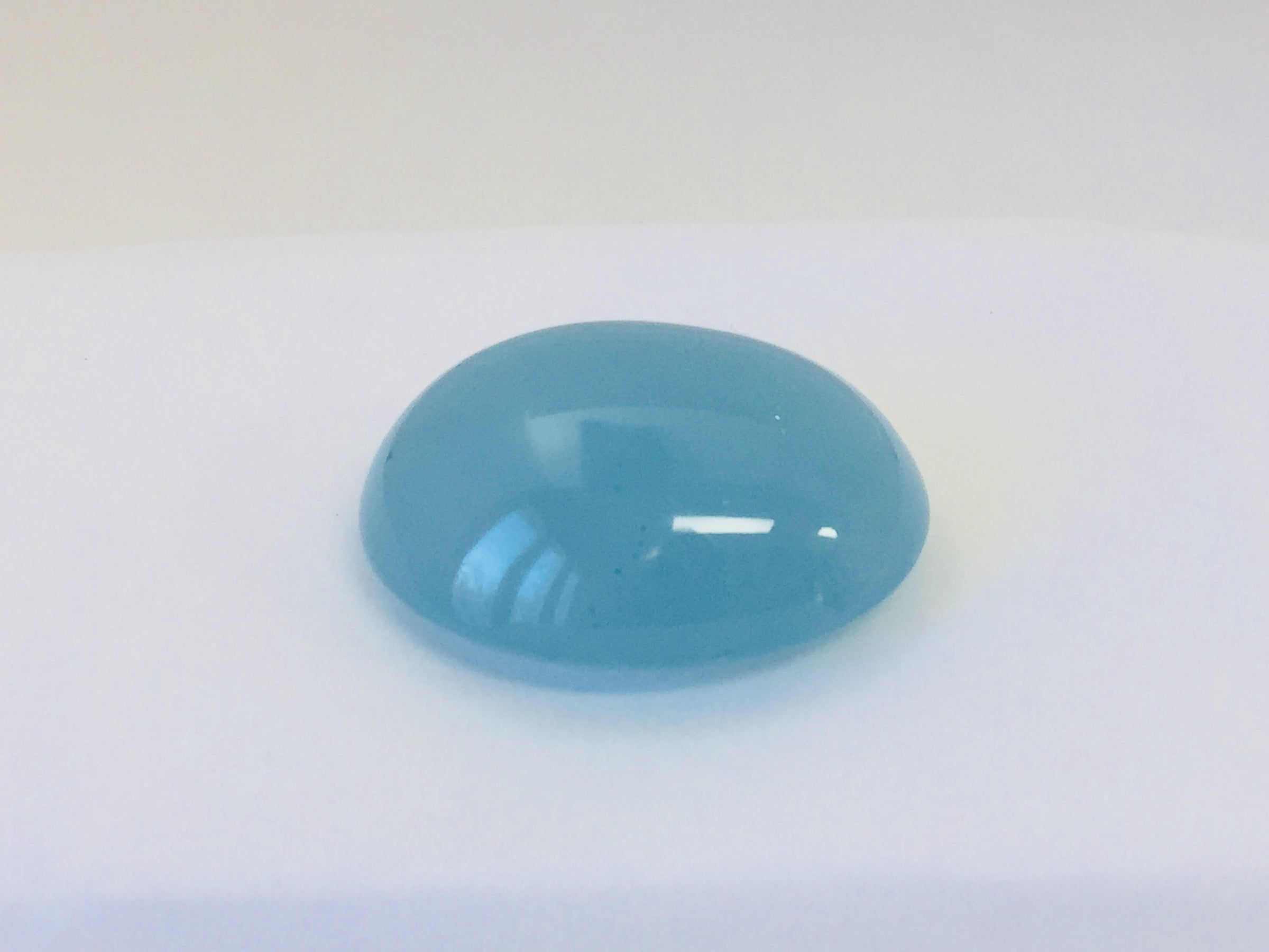 Large oval light blue cabochon aquamarine gem, white background.