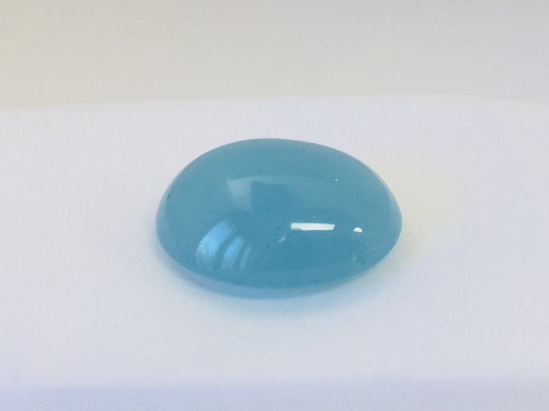 Large oval light blue cabochon aquamarine gem, white background.
