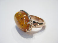 Very large oval amber set in rose gold ring.
