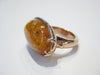 Very large oval amber set in rose gold ring.