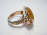 Very large oval amber set in rose gold ring.