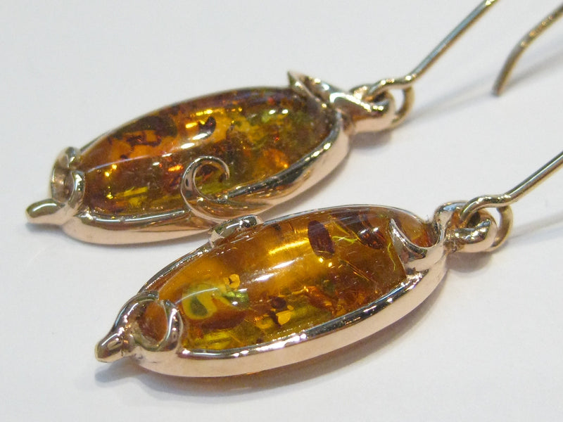 Pair of very large oval ambers set in rose gold earrings.