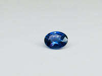 Small oval deep blue spinel gem, white background.