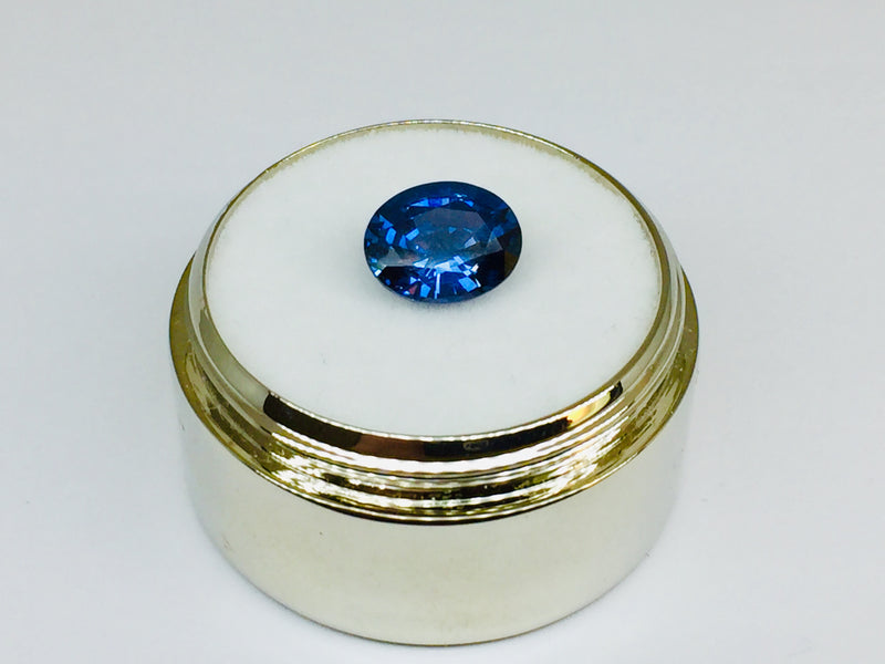 Small oval deep blue spinel gem, white background.