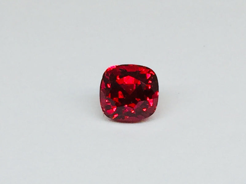 Deep red spinel gem, white background.