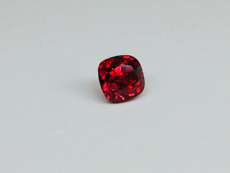 Deep red spinel gem, white background.