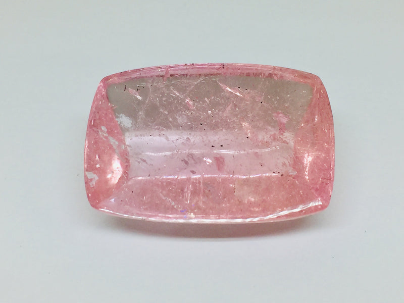 Very large cabochon of morganite (pink beryl) gem, white background.