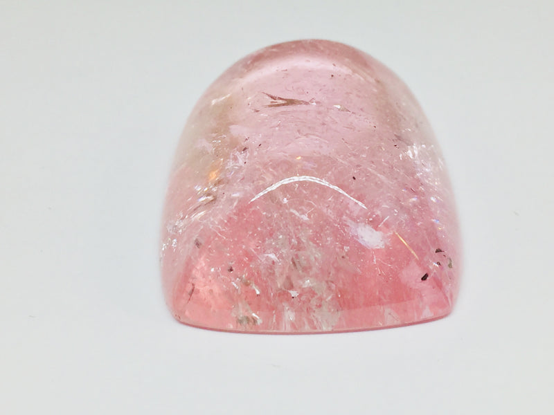 Very large cabochon of morganite (pink beryl) gem, white background.